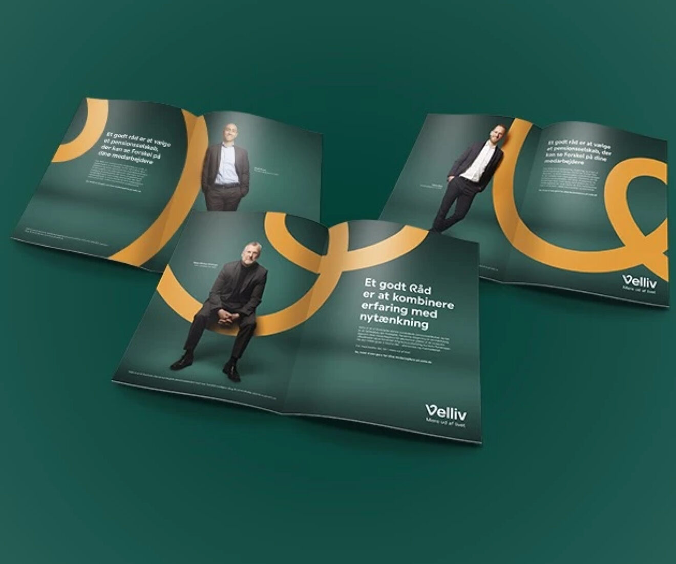 Three open Velliv brochures featuring portraits, Danish text, and sweeping yellow graphics on dark green backgrounds.