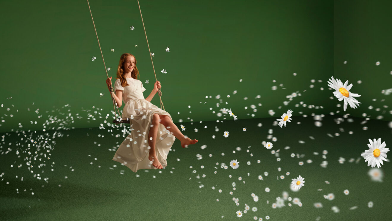 A woman in a white dress on a swing, surrounded by floating daisies against a green background.
