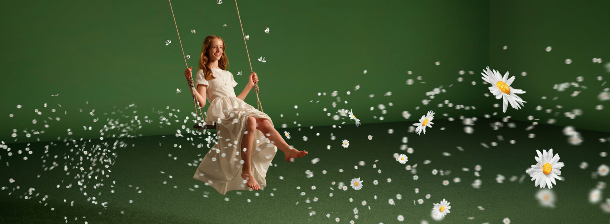 A woman in a white dress on a swing, surrounded by floating daisies against a green background.
