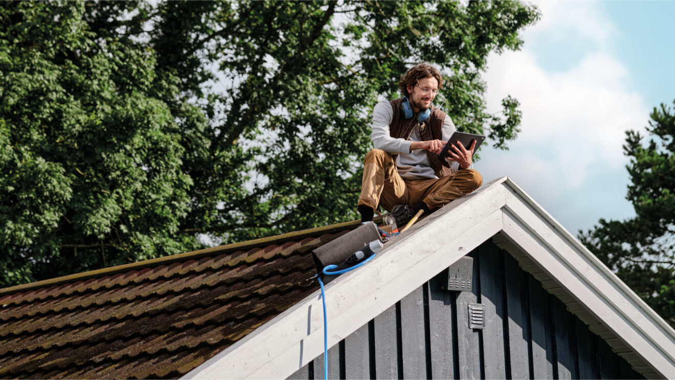 A carpenter sitting on a roof.