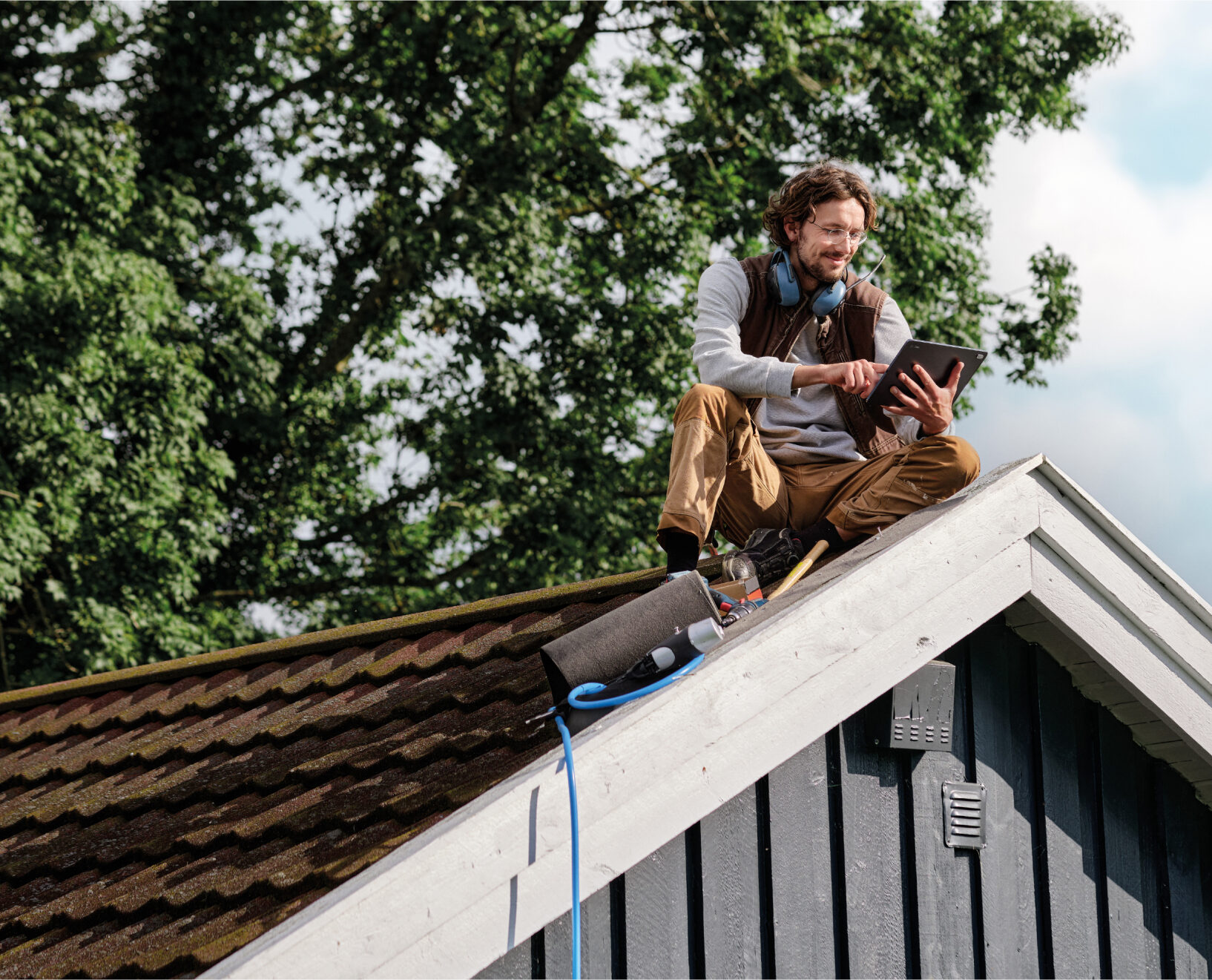 A carpenter sitting on a roof.
