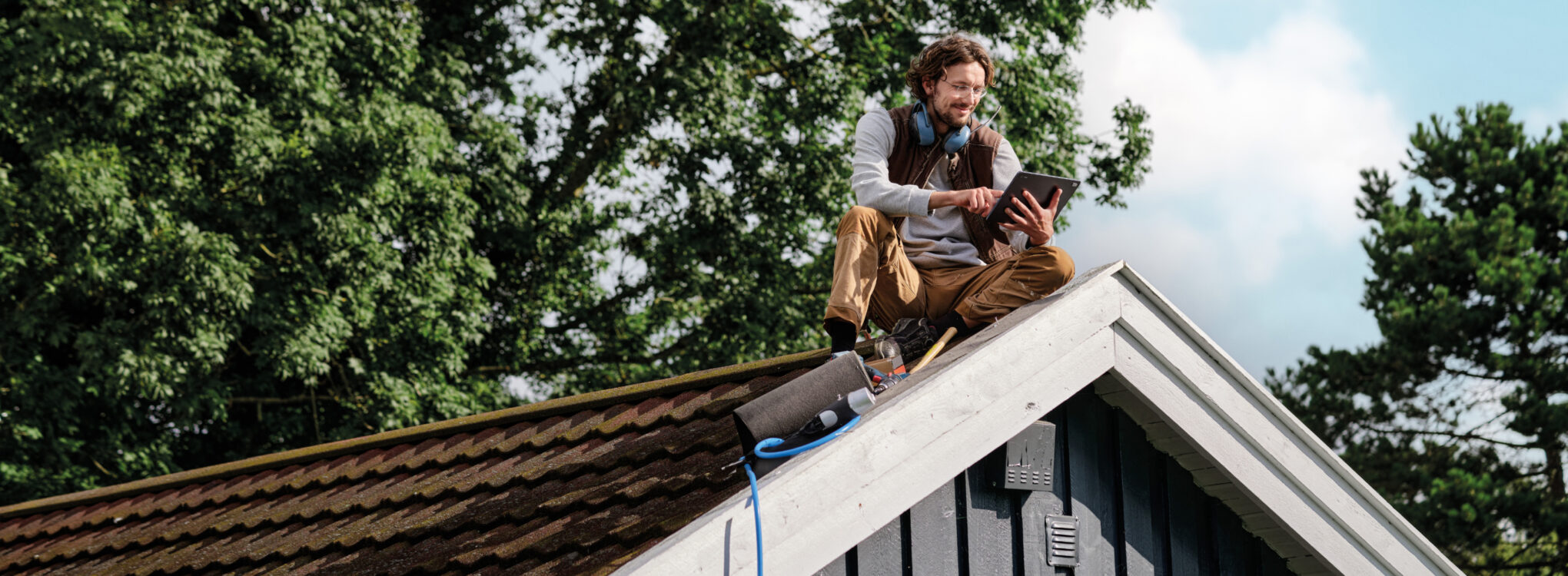 A carpenter sitting on a roof.