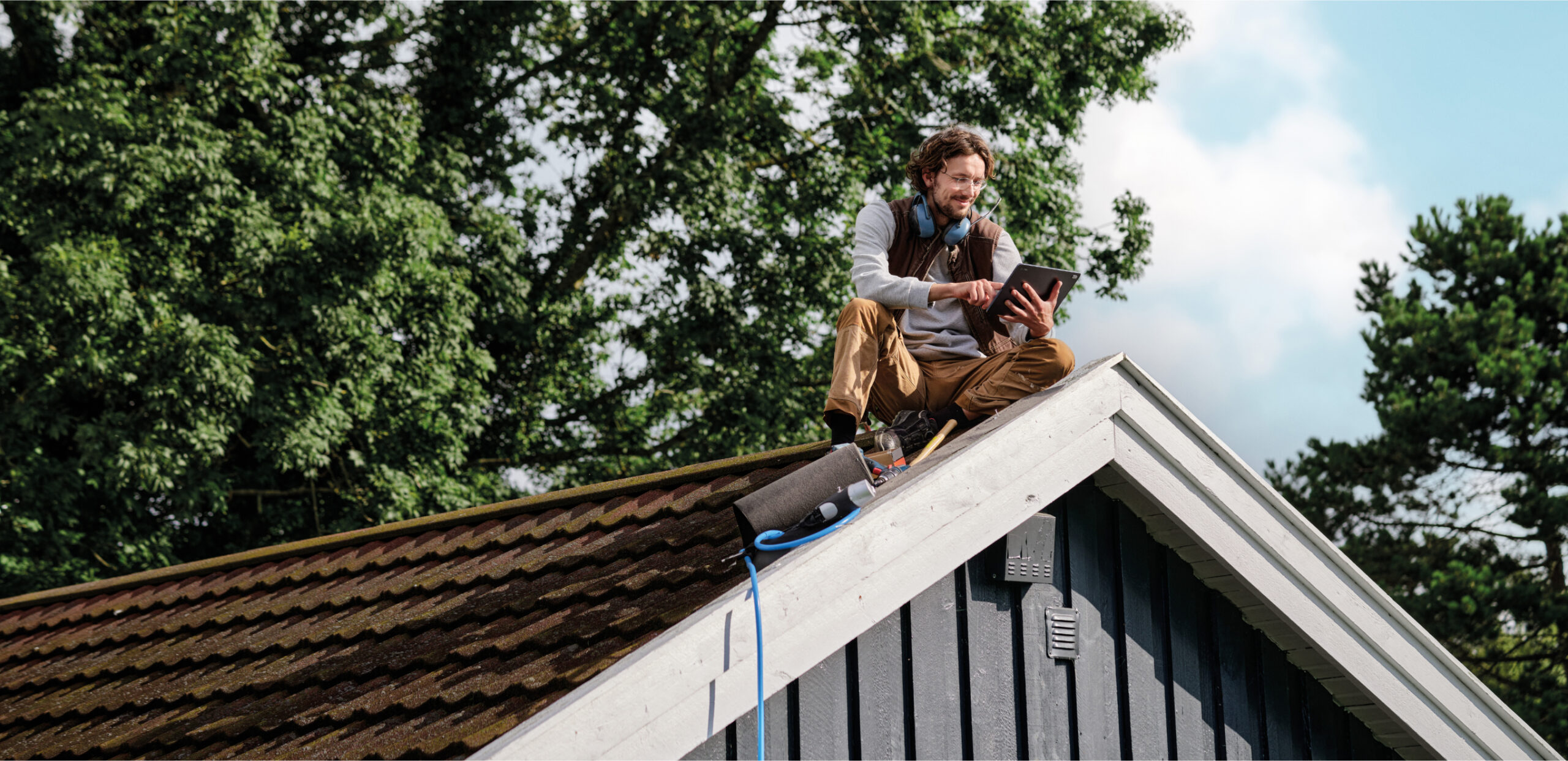 A carpenter sitting on a roof.