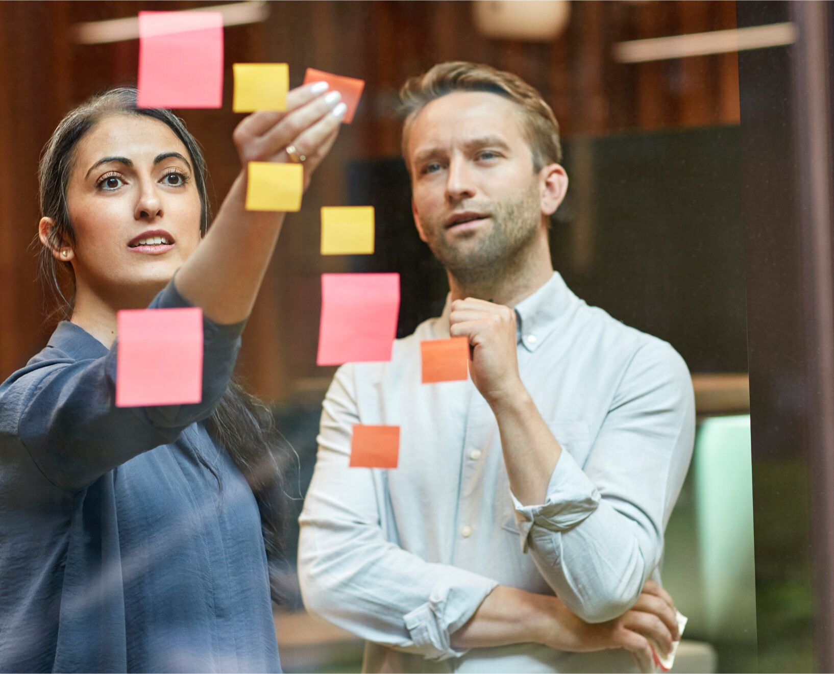 A woman and a man arranging sticky notes.
