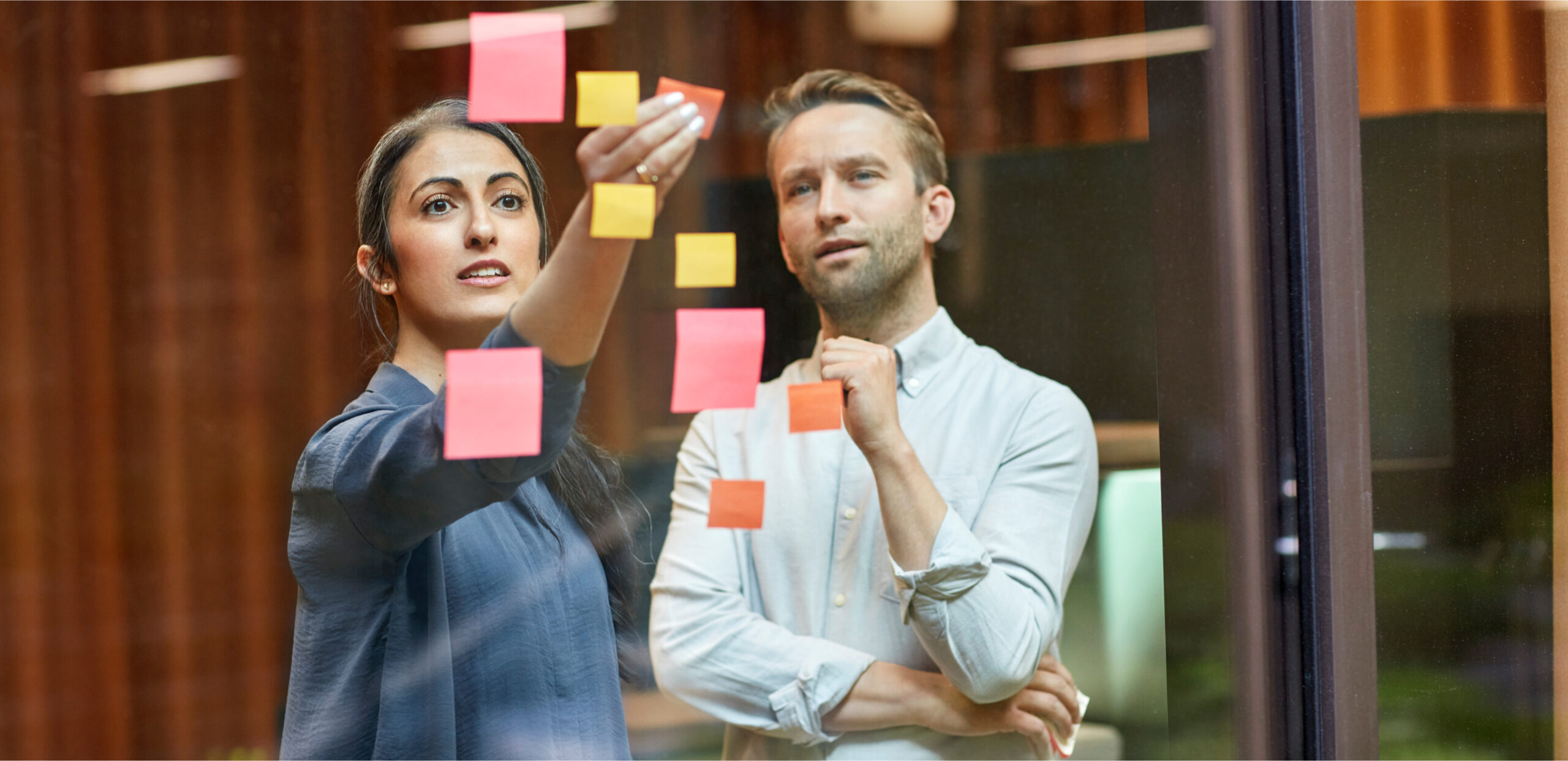 A woman and a man arranging sticky notes.