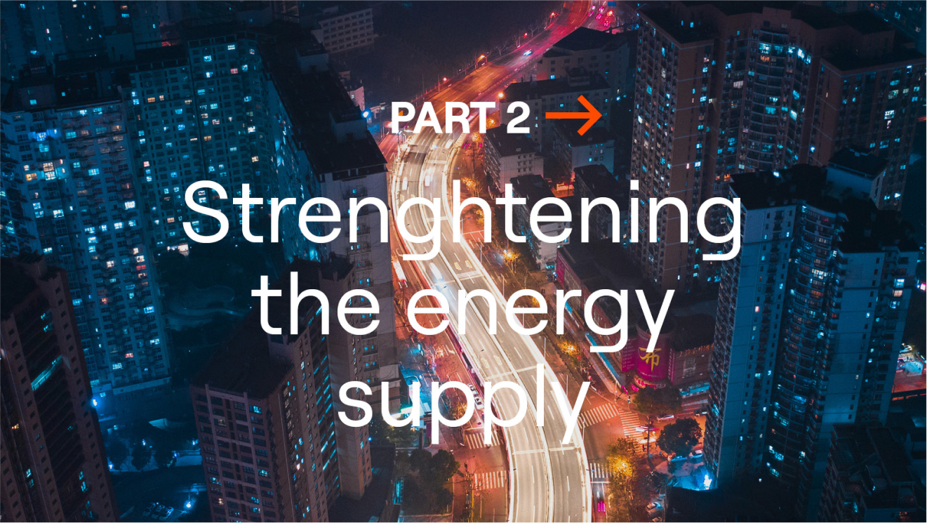 Night view of a city with illuminated roads winding between high-rise buildings, overlaid with the text “Part 2: Strengthening the Energy Supply”.