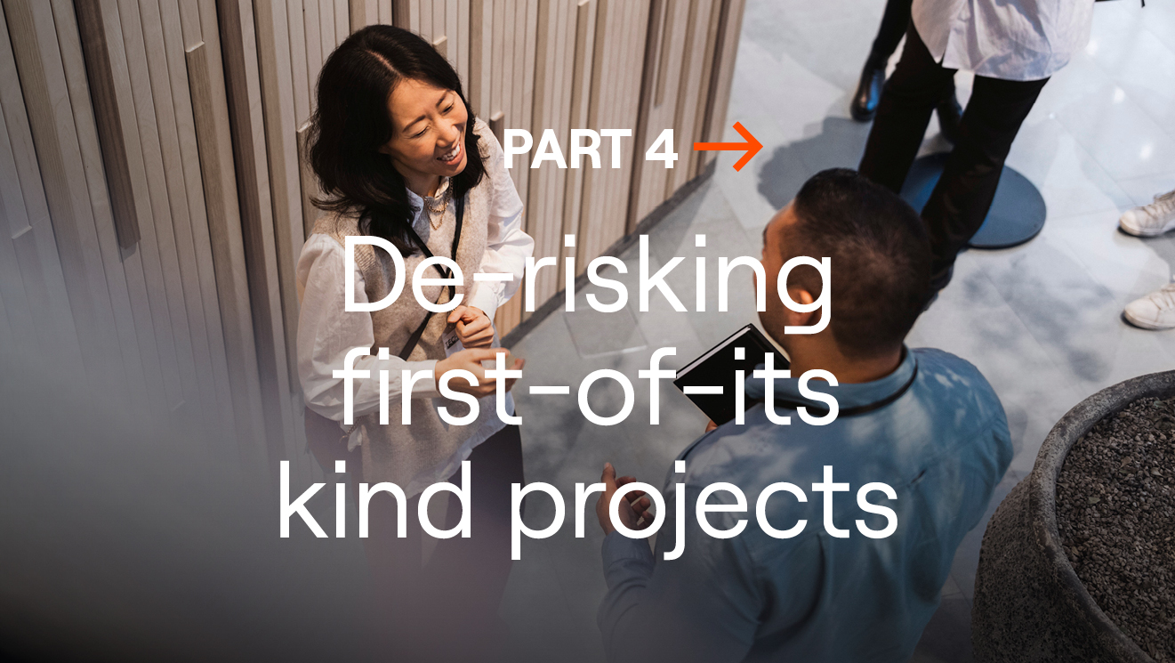 Two people talking at an event, with overlaid text reading “Part 4: De-risking first-of-its-kind projects”.
