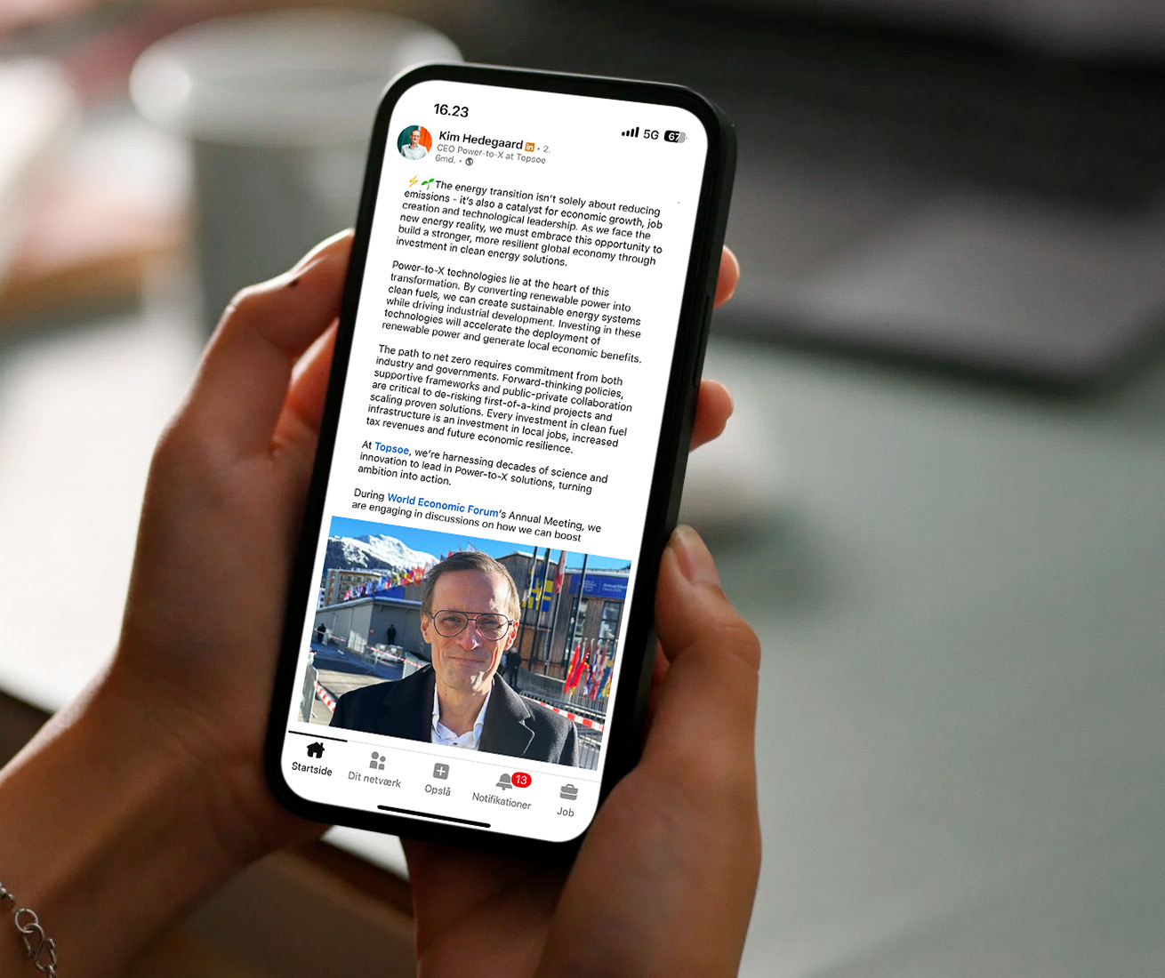 Close-up of a person holding a smartphone displaying a Topsoe LinkedIn post about the energy transition and Power-to-X technologies.