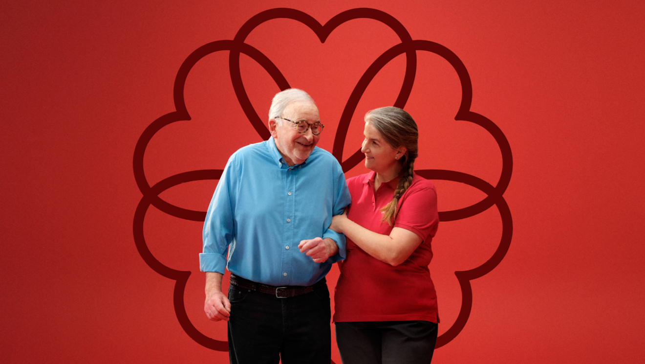 An older man and a woman smiling together against a red background.